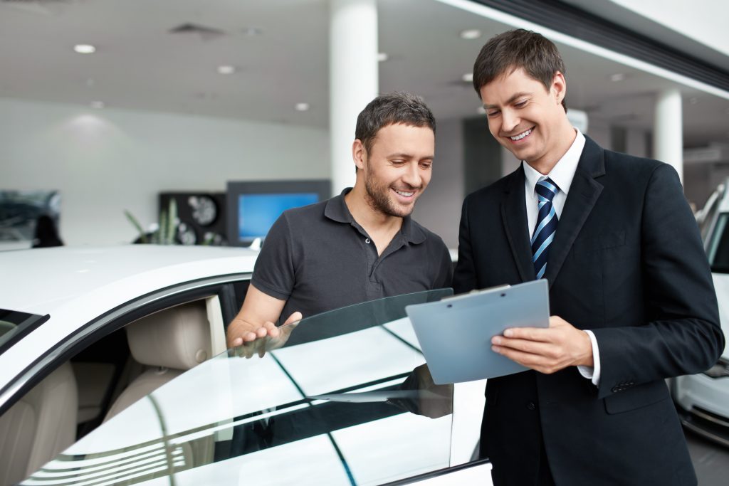 A car salesperson and customer discussing details in a showroom.