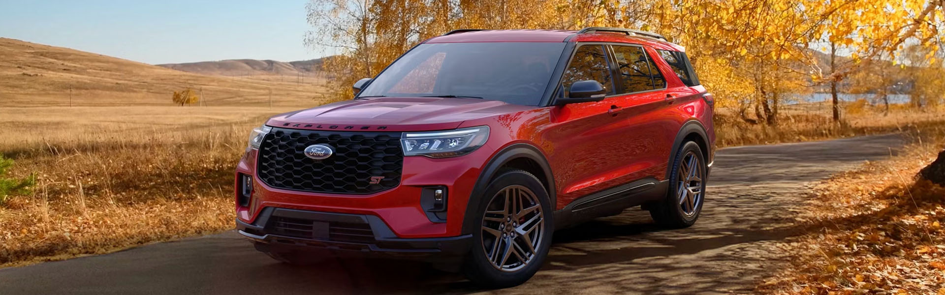 Red Ford SUV on a scenic autumn road.
